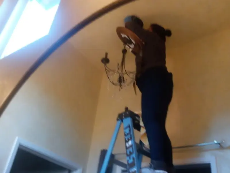 Electrician installing a chandelier in a Belton residence